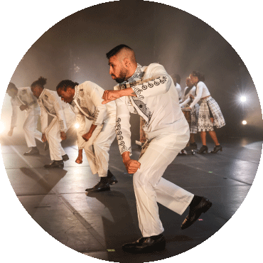 Group of dancers dressed in white perform on stage in a line