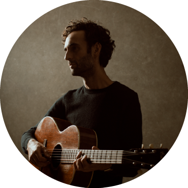 Shadowed portrait of Julian Lage holding the guitar.