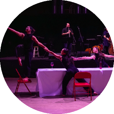 Dancers stretch to link arms and look to the left 