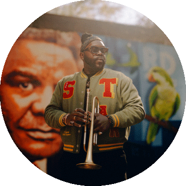 Marquis Hill stands and poses in front of a mural