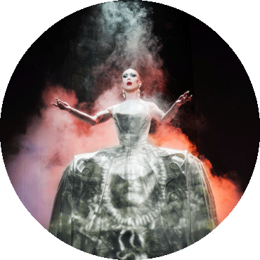 Sasha Velour performs with arms open and a light shining