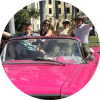 People having fun in a pink car with the top down.