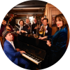 Eight members of the Hot Sardines pose together in a jazz cafe as they play their instruments.