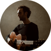 Shadowed portrait of Julian Lage holding the guitar.