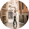 Marco Flores poses with his arms in the air in the alley way of an older looking city.