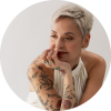 Mariza gazes to her left wearing a white dress against a white background.