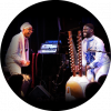 Omar Sosa and Seckou Keita are both wearing white patterned outfits on stage