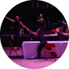 Dancers stretch to link arms and look to the left 