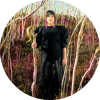 Maria Mazzotta stands among trees in a black outfit