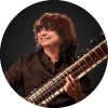 Niladri Kumaar smiles to the side and holds a sitar
