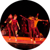 A group of dancers perform in red lighting