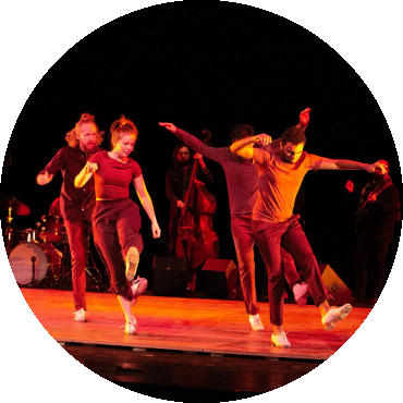 A group of dancers perform in red lighting