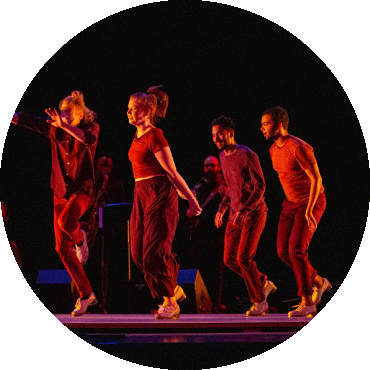 A group of dancers perform in red lighting