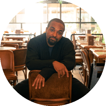 Solo image of bandleader Sullivan Fortner sitting on a chair